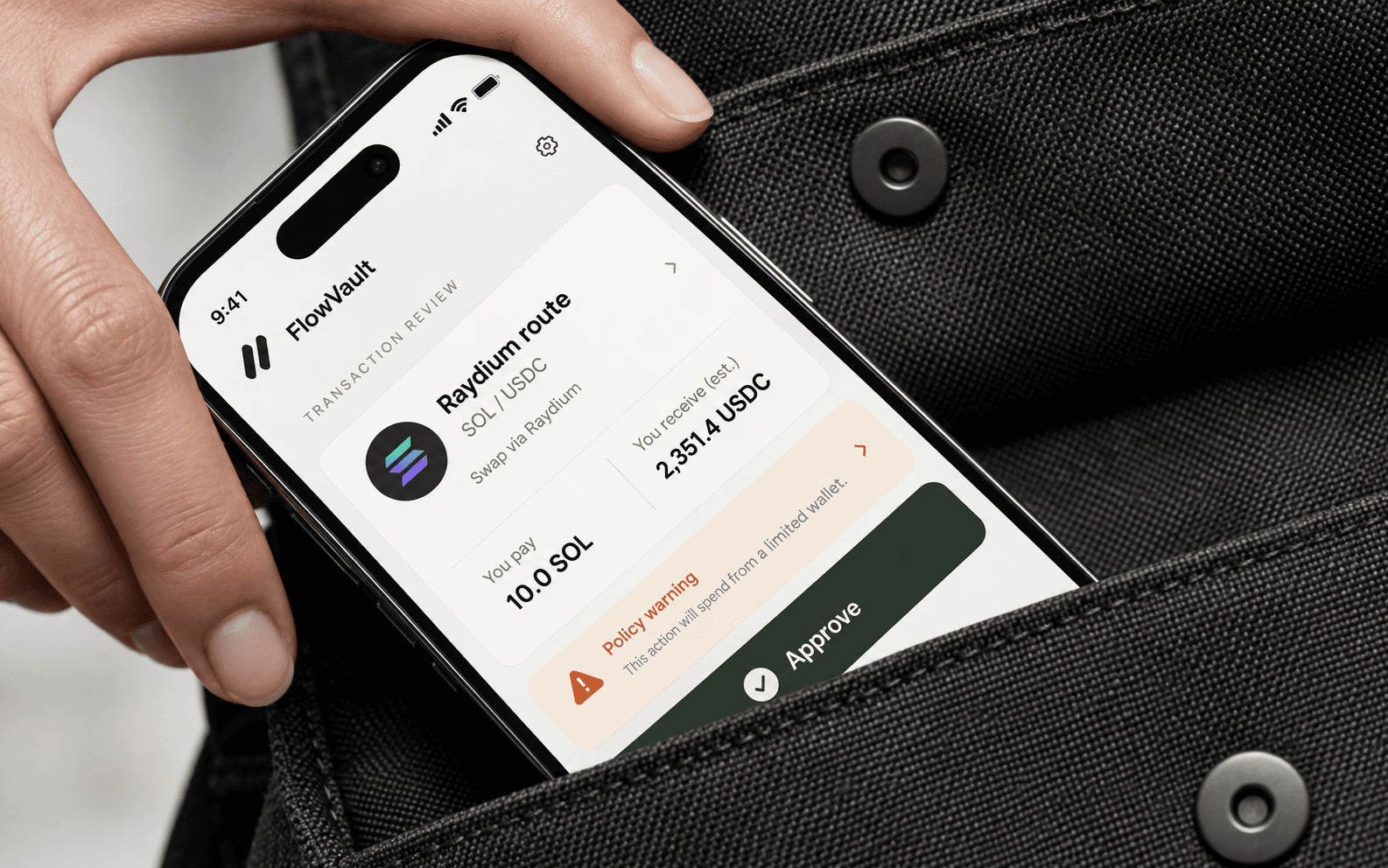 Phone showing a FlowVault approval interface tucked into a fabric pocket